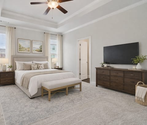 A bedroom with a large bed, a flat screen TV, and a ceiling fan.