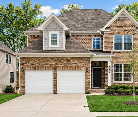 A house with a brown brick facade and a white garage door.