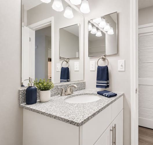 A bathroom with a sink, mirror, and towel rack.