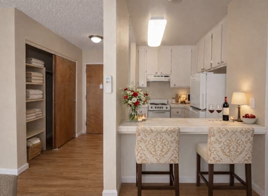 A kitchen with a white counter top and two chairs.