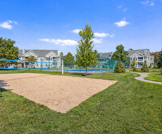 A sandy area in the foreground with a blue fence and a building in the background.