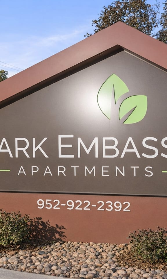 A sign for Park Embassy Apartments with a phone number on it.