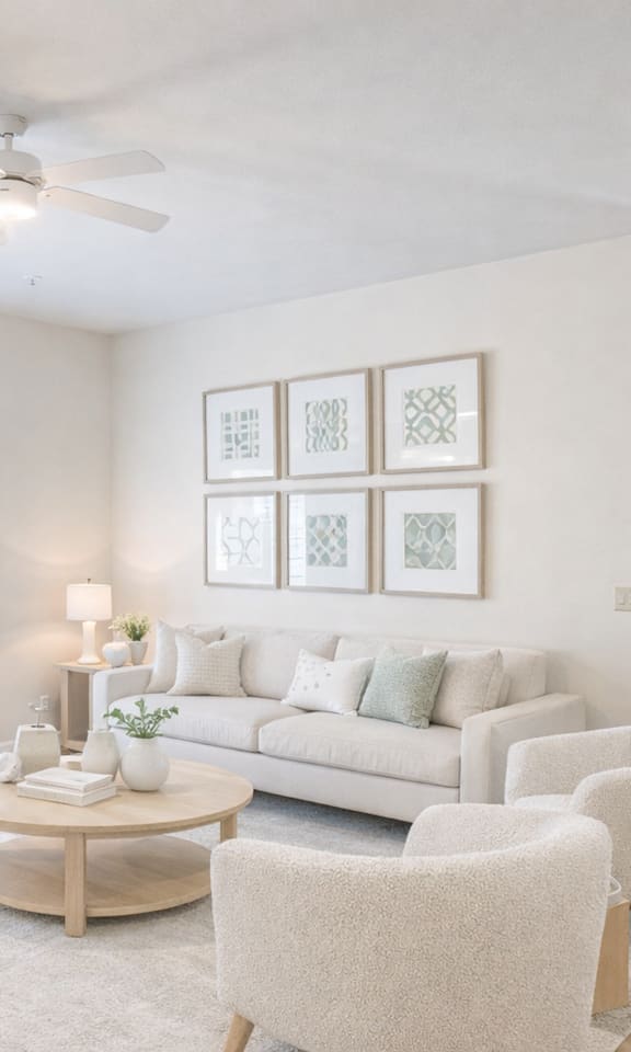 A living room with a couch, chairs, and pictures on the wall.