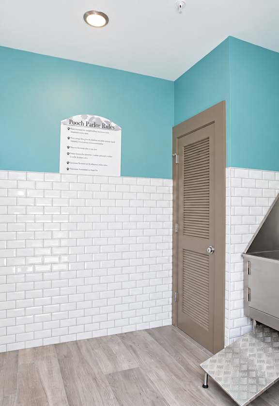A bathroom with a white tiled wall and a wooden door.