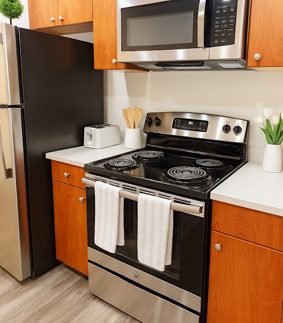 A kitchen with a stainless steel refrigerator and wooden cabinets.