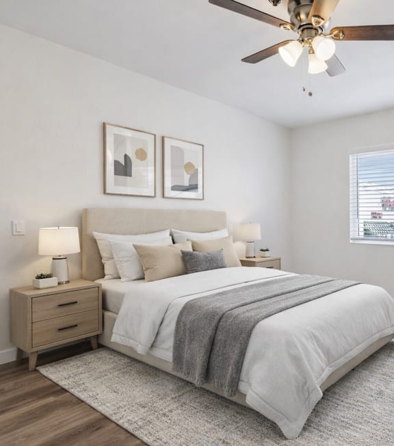 A well-lit bedroom with a large bed and a painting on the wall.