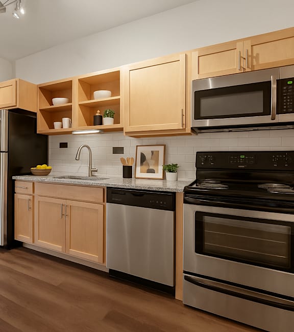 A kitchen with wooden cabinets and stainless steel appliances. at B Street Lohi Apartments, Denver, CO