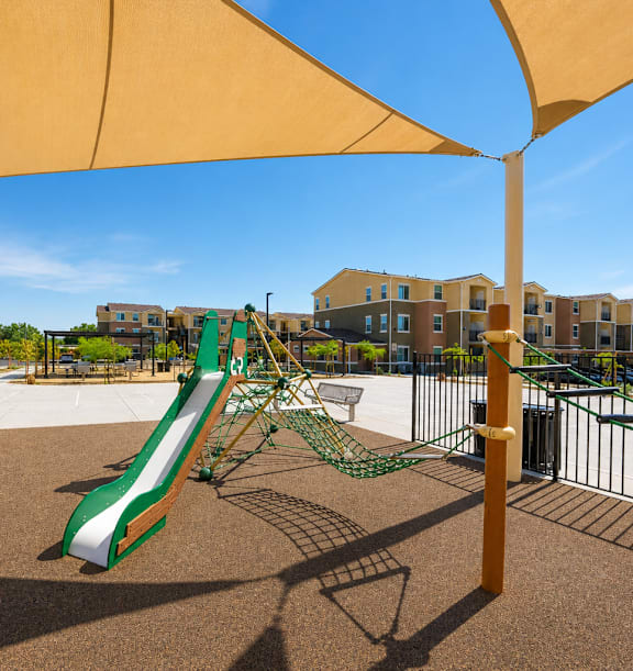 A playground with a green and white slide under a yellow canopy.