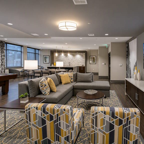 A modern living room with a grey couch, a coffee table, and a large TV on the wall.