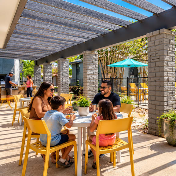 A family enjoys a meal together at an outdoor dining area.