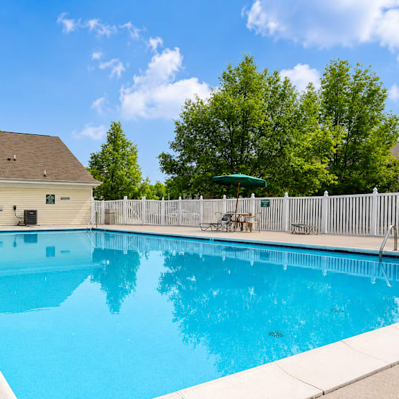 A small pool in a backyard with a white fence.