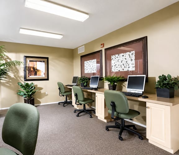 A room with a desk, chairs, and computers.