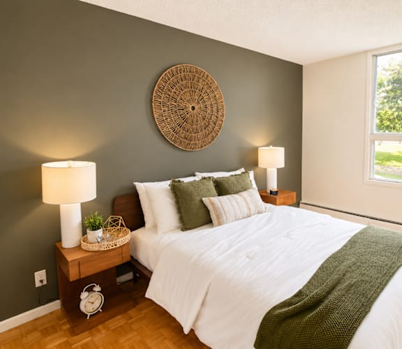 A bedroom with a white bed and a green blanket.