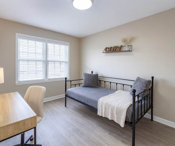 A bedroom with a bed, chair, and desk.