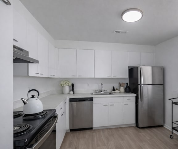 A modern kitchen with white cabinets and stainless steel appliances.