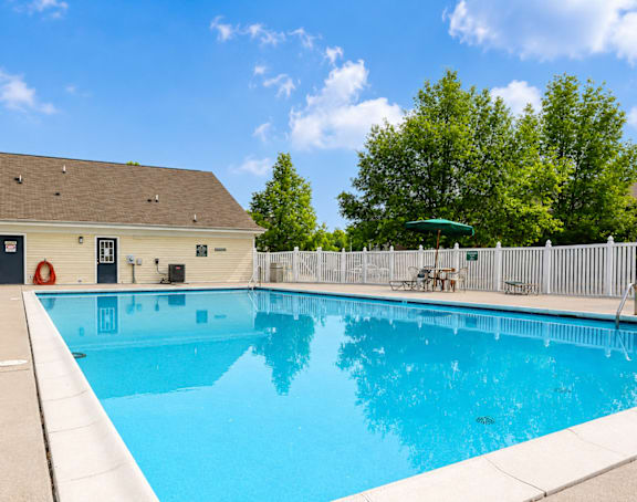 A small pool in a backyard with a white fence.