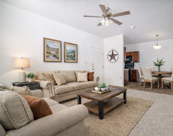 A living room with a beige couch, a coffee table, and a ceiling fan.