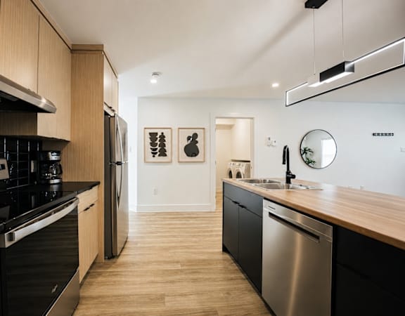 A modern kitchen with black appliances and wooden cabinets.