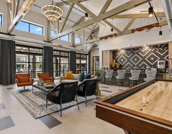 Modern resident clubhouse with shuffleboard  lounge seating, and contemporary finishes at One Preston Station.