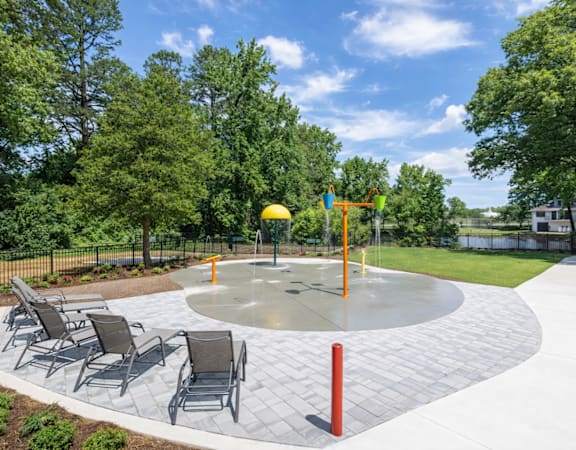 A playground with a round concrete structure and chairs.