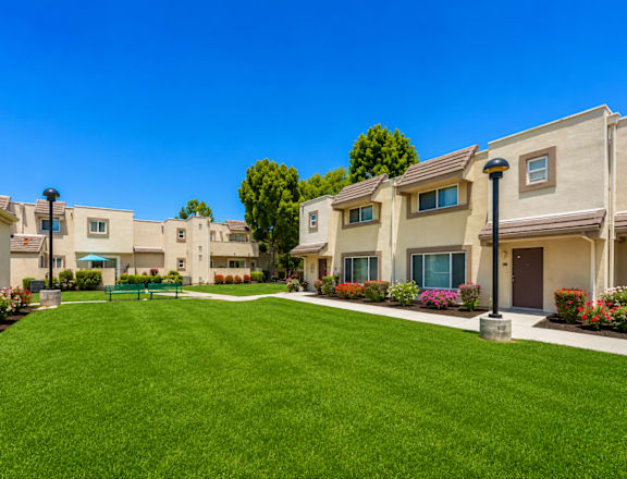 A row of houses with a green lawn in front.