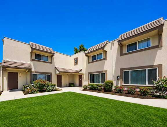 A row of houses with a green lawn in front.