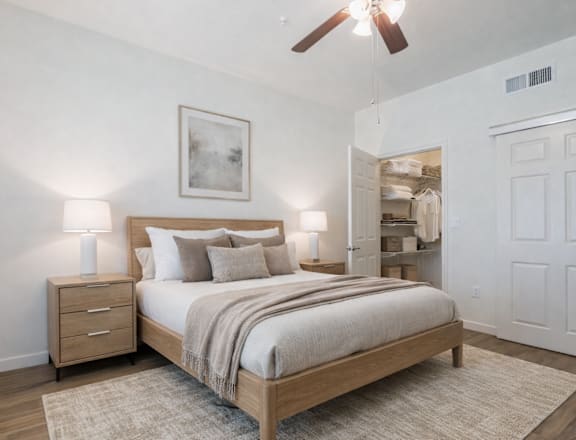 A bedroom with a bed, nightstand, and a painting on the wall.