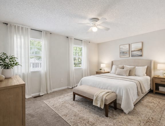 A bedroom with a large bed, a ceiling fan, and a window with curtains.