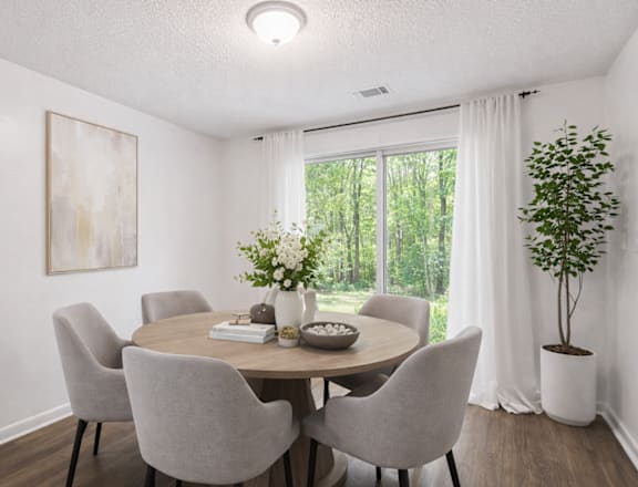 A dining room with a round table and grey chairs.