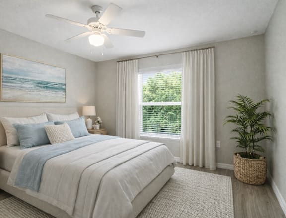 A bedroom with a large bed, a ceiling fan, and a painting of a beach scene on the wall.