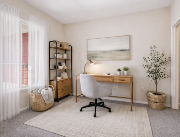 A room with a desk, chair, and a basket on the floor.