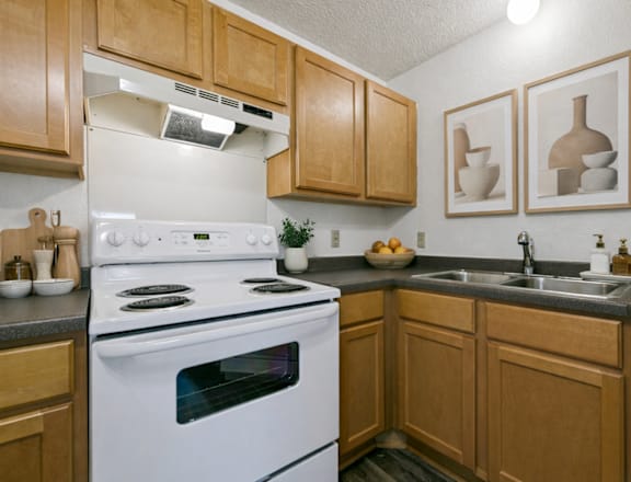 A kitchen with wooden cabinets and a white stove top oven.