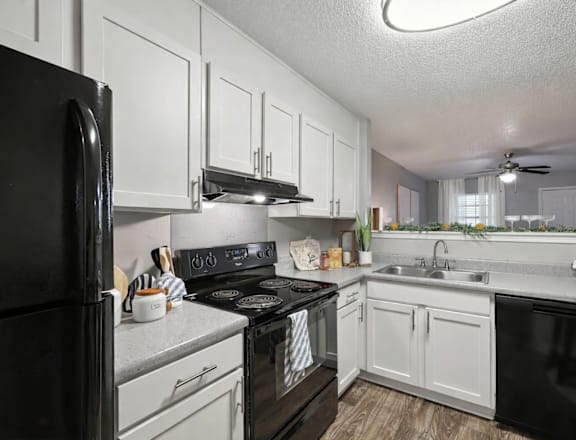 A black stove top oven sits in a kitchen with white cabinets.