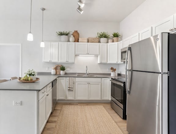 A modern kitchen with a stainless steel refrigerator and white cabinets.