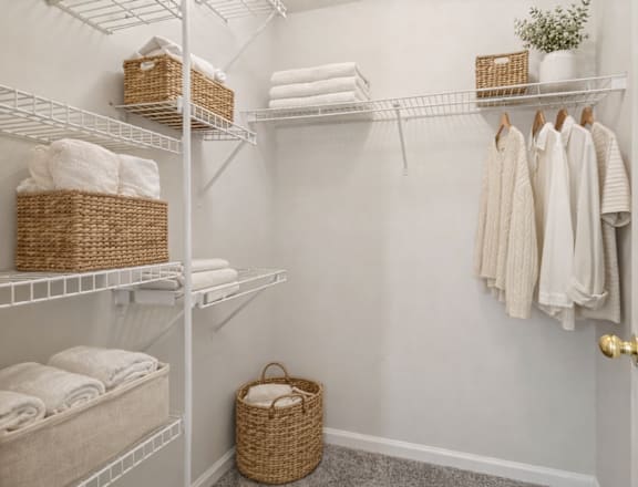 A white closet with towels and baskets on the shelves.