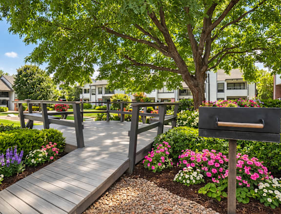 A wooden bridge over a garden with a mailbox on the right.