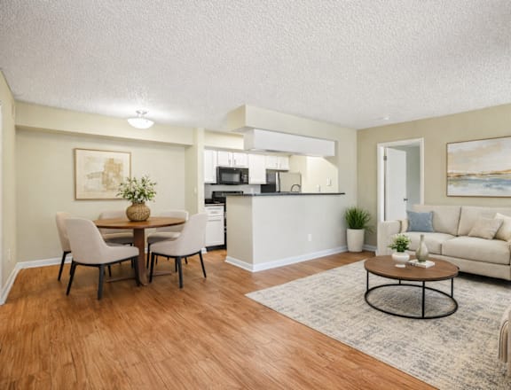 A living room with a white couch and a dining table with chairs.