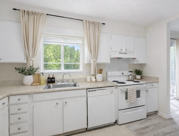 A white kitchen with a window and curtains.