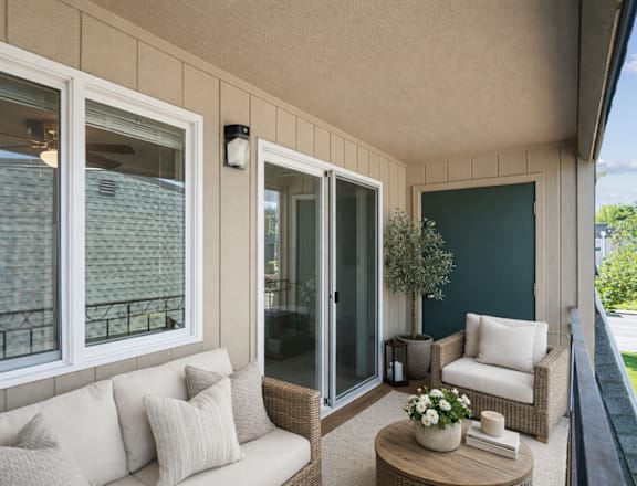 A balcony with a sofa, chairs, and a coffee table.