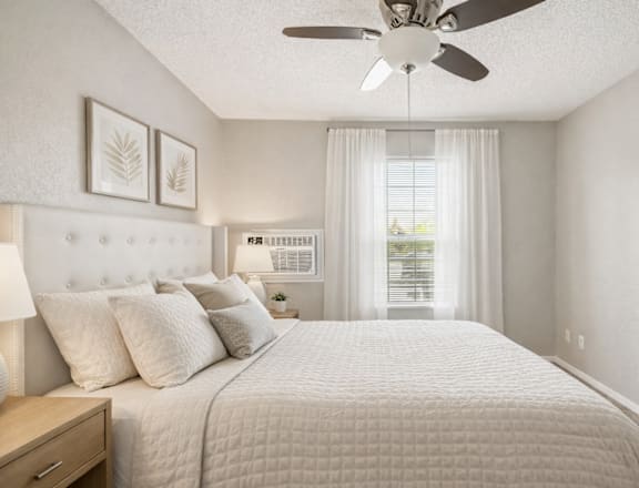 A bedroom with a large bed and a ceiling fan.