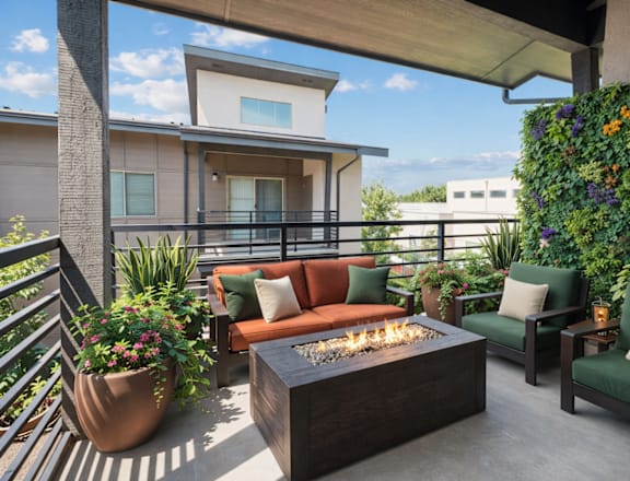 A patio with a fire pit, two chairs, and a planter.