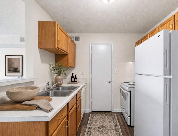 A kitchen with a white refrigerator and wooden cabinets.