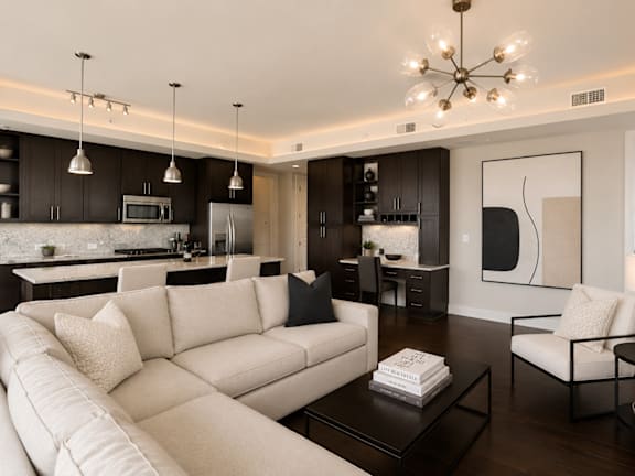 A living room with a beige sofa, orange armchair, and a coffee table. at Uptown by Onni Apartments, Apartments, Dallas, TX