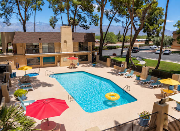 A pool surrounded by chairs and umbrellas.