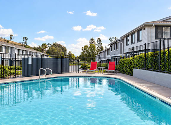 A swimming pool in front of a row of houses.