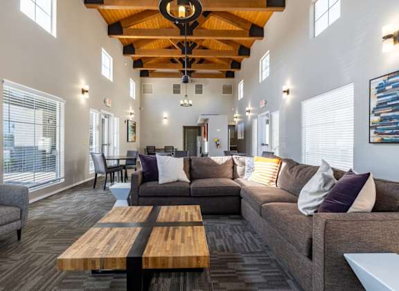 A modern living room with a wooden ceiling and grey couches.