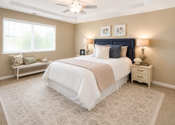 A bedroom with a large bed and a window with blinds.