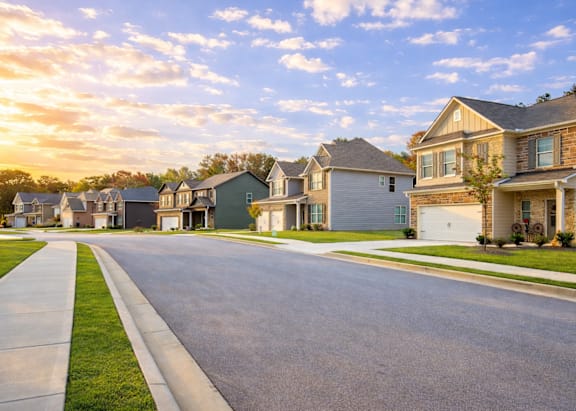 A row of houses with a sidewalk in front of them.