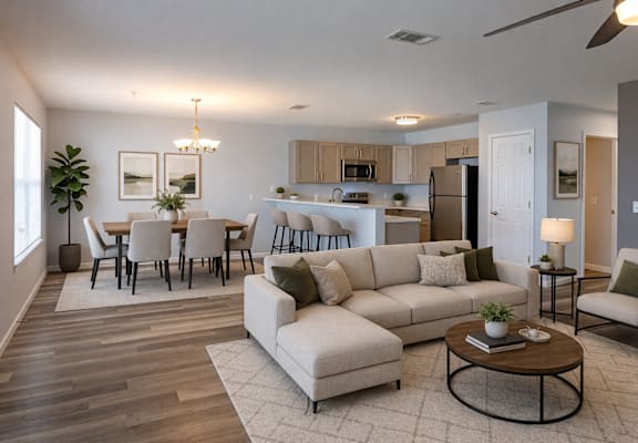 A well-lit, modern living room with a dining area and kitchen in the background.
