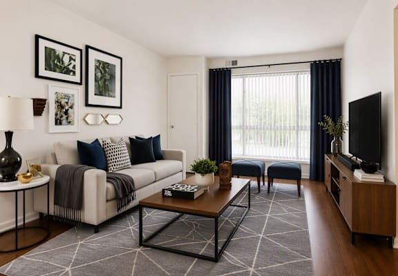 A living room with a white couch, a coffee table, and a television.